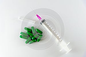 Empty medical syringe, needle and green pills