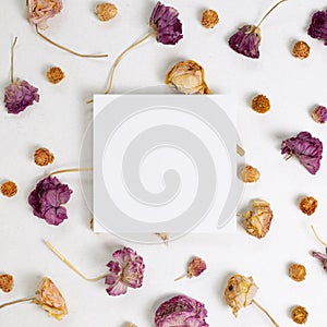 Empty memo paper with dry ranunculus and globe amaranth flowers on white background