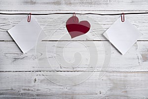 Empty memos and heart hanging on ribbon, wooden wall