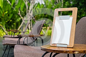 Empty menu frame standing on wood table in outdoor cafe near the