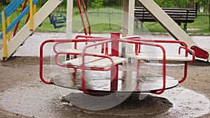 Empty merry go round carousel is wet in the rain, turns lonely in wind. a heavy rain, downpour with a strong wind. large