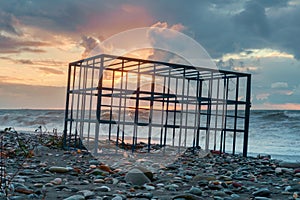 Empty metal cage on the sunset beach