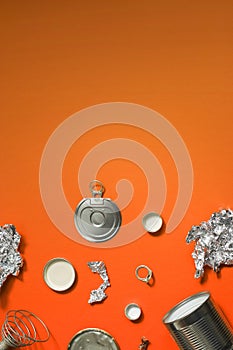 Empty metal products, cans, lids awaiting processing. Trash on an orange background