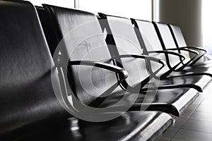 Empty metal seats with black leather seat in the public area at an airport