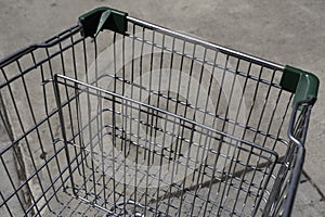 Empty metal shopping cart with shadow outside a supermarket