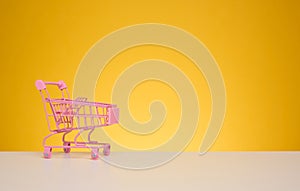 Empty miniature shopping cart on a blue background. Seasonal sale