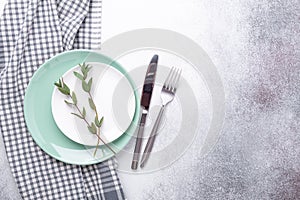 Empty mint and white plates  linen napkin  eucalyptus leaves and cutlery on stone background Copy space Top view