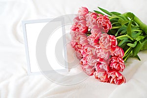 Empty mockup frame near the bouquet of pink peony tulips on the soft blanket