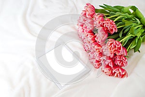 Empty mockup place near the bouquet of pink peony tulips on the soft blanket