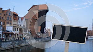 Empty mockup template Blackboard label against Gdansk beautiful old town over Motlawa river. The Zuraw Crane and