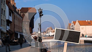 Empty mockup template Blackboard label against Gdansk beautiful old town over Motlawa river. The Zuraw Crane and