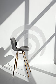 Empty modern chair in room, stine sunlight, white walls. Minimalistic interior, concept of cleanliness, loneliness, calm,