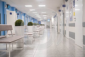 Empty modern hospital corridor, clinic hallway interior background with white chairs for patients waiting for doctor visit.