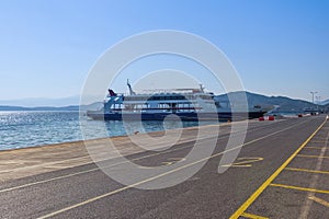 An empty moored car ferry boat docked at the port around the calm sea on a bright summer day in Greece