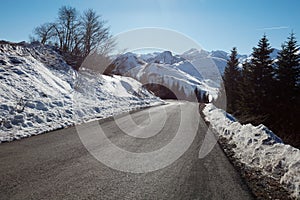 Empty mountain road descent on Alps, blue sky