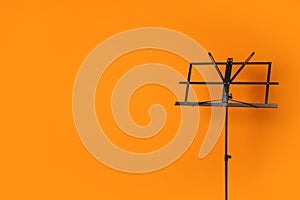 Empty music note stand on color background