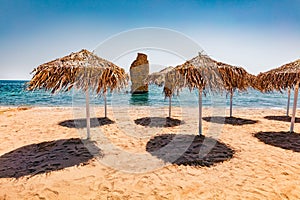 Empty Mylos Beach with sun umbrellas and ruins of old Roman tower on background. photo
