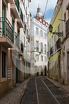 Empty narrow cobblestone street or alley with tramway rails, Lisbon, Portugal