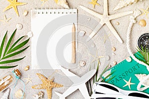 Empty notebook with accessories for planning summer holidays, travel and vacation on sand background top view. Flat lay style