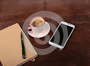Empty notebook and ball pen with a cup of coffee, phone of the office desk. Business concept