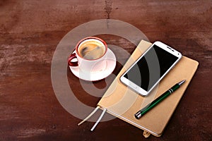 Empty notebook and ball pen with a cup of coffee, phone of the office desk. Business concept