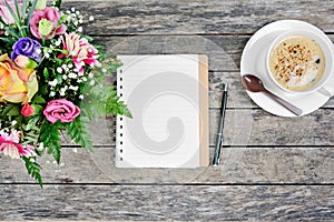 Empty notebook with pen, coffee cup and colorful flowers on table
