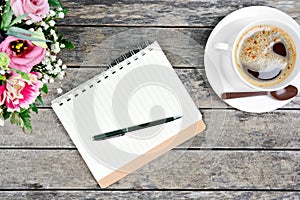 Empty notebook with pen, coffee cup and colorful flowers on table