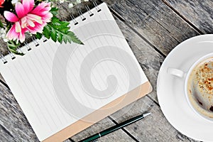 Empty notebook with pen, coffee cup and flowers on table