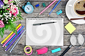 Empty notebook with pen, colorful pencils, clock, flowers and coffee cup