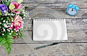 Empty notebook with pen, flowers and clock