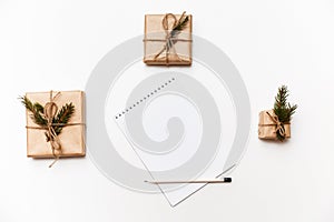 Empty notebook, pencil and gift boxes or presents packed in kraft paper isolated on white, top view