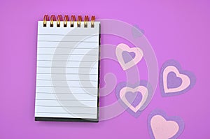 empty notebook on purple background with hearts