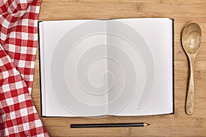 Empty notebook for recipes with spoon on wooden