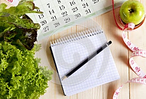 Empty notebook with vegetable salad and apple