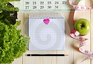 Empty notebook with vegetable salad and apple