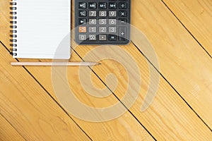 Empty notepad and calculator and pencil on wooden desk, copy space, top view background