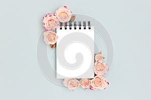 Empty notepad mock up. Pink rose flowers on a blue background.