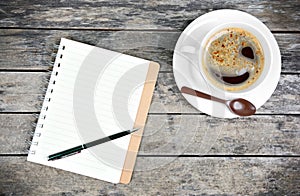 Empty notepad with pen and coffee cup on table