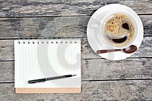 Empty notepad with pen and coffee cup on table