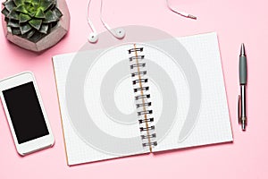 Empty notepad, smartphone and cactus on pink top view.