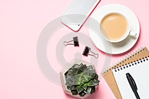 Empty notepad, smartphone and cactus on pink top view.