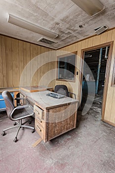 Empty office with desk covered in dust in an abandoned factory