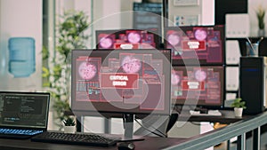 Empty it office desk with multiple computers showing security breach warning