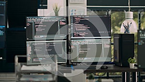 Empty office desk with multiple screens running software developing script