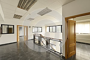 Empty offices with gray stoneware floors, metal railing, wood