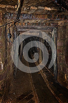 Empty old abandoned mine shaft with wooden timbering and rusty railway photo