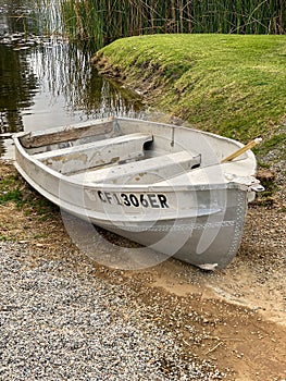 Empty old decaying metal row boat grounded at a swamp lake pond