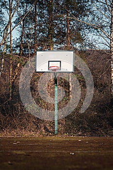 Empty old Empty old basketball court with basketball hoop with trees court with a new basketball hoop with trees in the background