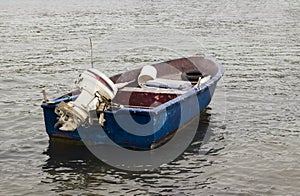 Empty and old fishing boat with engine moored on the blue sea