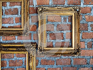 Empty old ornate golden frames hanging on brick wall